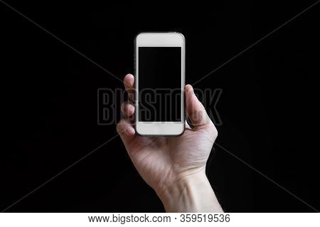 Man Holding Smartphone With Empty Screen Isolated On Black Background. Male Hands With Phone, Space 