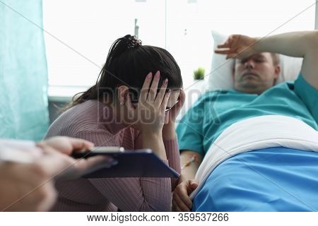 Upset Woman Sitting Near Man In Hospital Bed. Resuscitation Measures For Critically Ill Patients. As