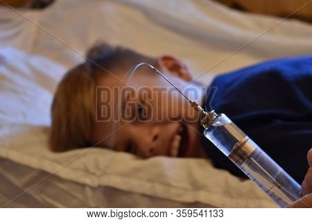 The Boy Is Afraid Of Injections. The Pediatrician With A Syringe. Baby Medical Syringe. Compulsory T