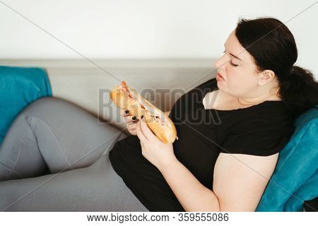 Overeating And Gluttony Concept. Mindless Snacking, Home Sedentary Lifestyle. Obese Woman Sitting On