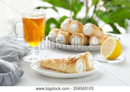 Puff Pastry Horn With White Cream. Fresh Dessert Roll With Cream Or Meringue And Tea With Lemon On A