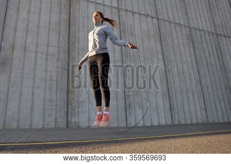 Portrait Of Fit Young Woman With Jump Rope Outdoors. Fitness Female Doing Skipping Workout Outdoors 