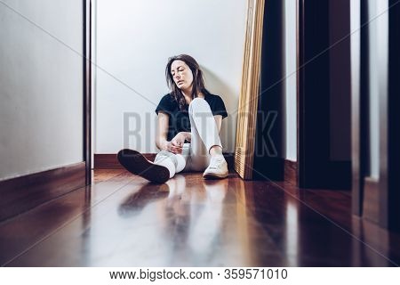 Abused Woman Sitting On The Floor Of Her Home With Signs Of Violence On Her Face