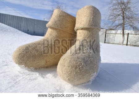White Felt Boots Close-up. Snow Stuck To The Boots. Valenoks Are Covered With Small Ice Floes.