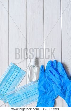 Medical Protective Mask, Rubber Gloves, Antiseptic And White Anti-irus Tablets Lie On A White Wooden