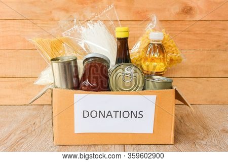 Donations Box With Canned Food On Wooden Table Background / Pasta Canned Goods And Dry Food Non Peri