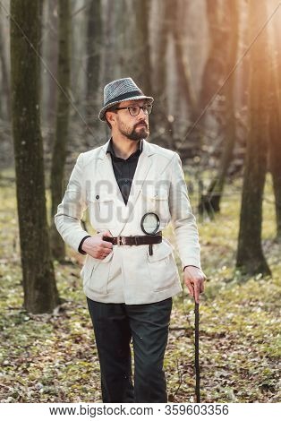Portrait Of Pensive Presentable-looking Man Leaning On Stick Standing In Early Spring Deciduous Wood