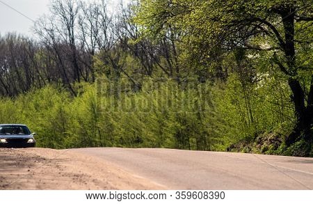 The Road In The Forest. Car With Headlights On The Rise Of A Forest Road. Selective Focus.