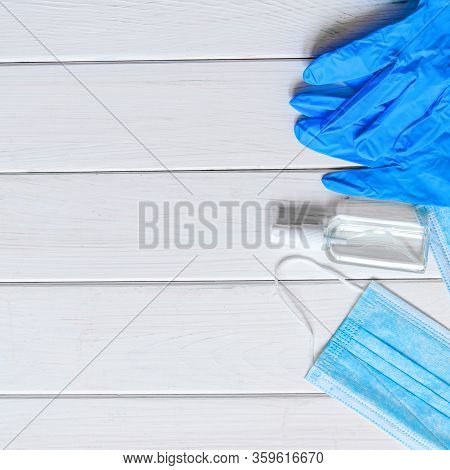 Medical Protective Mask, Rubber Gloves, Antiseptic And White Anti-irus Tablets Lie On A White Wooden