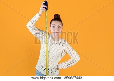 Surprised Smiling Girl Stands Next To A Stretched Measuring Tape And Measures Her Height, Isolated O