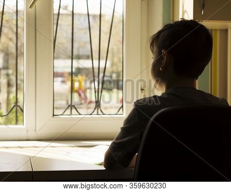 The Quarantined Boy Sadly Looks At The Street Through The Window, There Is Covid-19