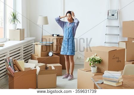 Full Length Portrait Of Frustrated Asian Woman Panicking While Standing Among Cardboard Boxes In Emp