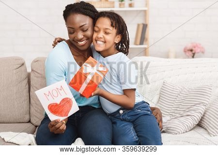 Congatulations. Black Kid Embracing Mom, Giving Gift Box And Greeting Card To Her, Copyspace