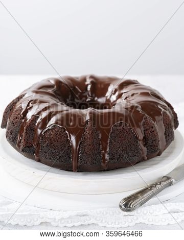 Homemade Chocolate Bundt Cake With Melted Chocolate On Plate On White Background With Copy Space. Cl