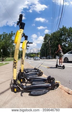 Atlanta, Ga/usa - August 10:  A Young Woman Riding A Motorized Scooter Passes By Several Parked Scoo