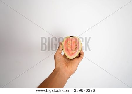 Female Hand Holding A Half Of Ripe Guava On A White Background.