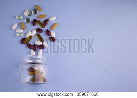 Food Supplements In Bottle Of Glass In Blue Background