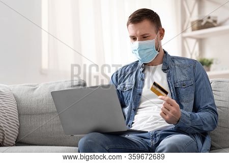 Safety Shopping At Home. Young Man In Protective Mask Buying Food Online, Empty Space