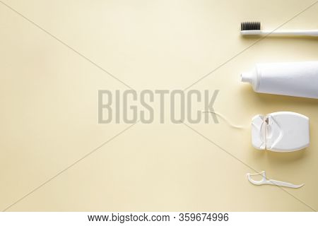 Toothbrush, Toothpaste And Dental Floss On A Yellow Background With Space For Text. Flat Lay.
