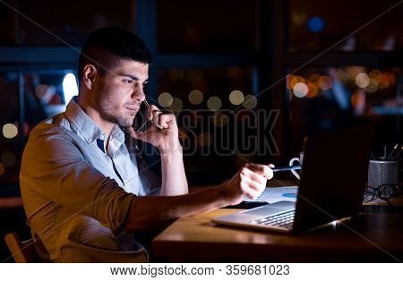 Remote Work. Businessman Talking On Phone With Distant Colleague Discussing Project Sitting In Offic