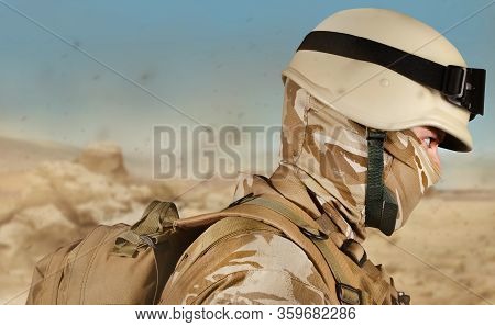 Photo Of A Desert Soldier In Uniform With Helmet And Backback, Profile View On Desert Background.