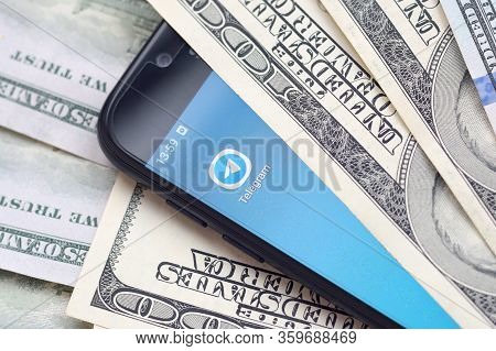 Smartphone Screen With Telegram App And Lot Of Hundred Dollar Bills. Business And Social Networking 