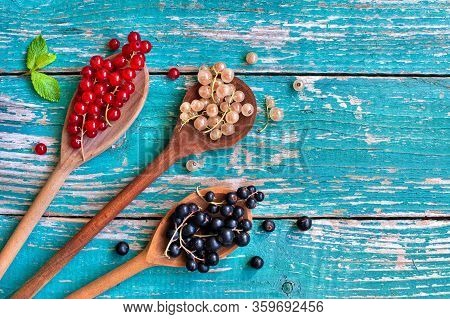 Mix Of White Currant, Red Currant And Black Currant In Different Spoons On Vintage Wooden Backglound