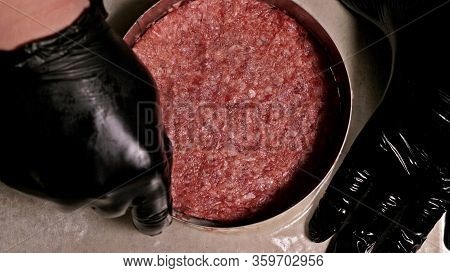 Cook Makes Meat Medallions For Burgers. Chef In Black Food Gloves Makes Cutlet. Cutlets Are Leveled 