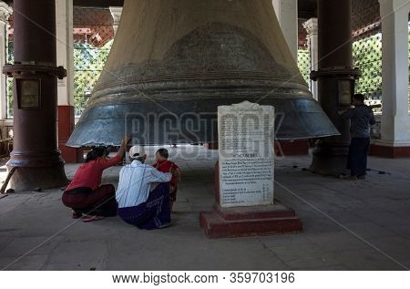 Mingun, Myanmar - January 13, 2020: Burmese family looking under Mingun Bell - 2nd largest bell in the world