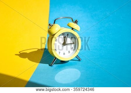 Yellow Vintage Alarm Clock On A Blue And Yellow Background With Selective Focus, Copy Space For Text