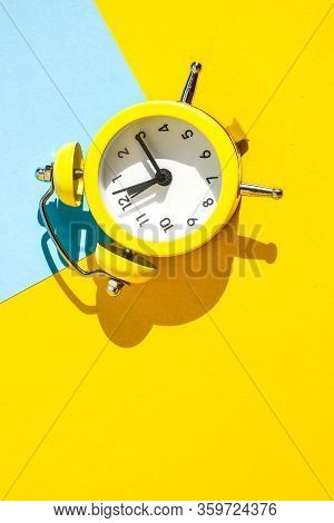 Yellow Vintage Alarm Clock On A Blue And Yellow Background With Selective Focus, Copy Space For Text