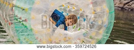 Cute Little Boy, Playing In Zorb A Rolling Plastic Cylinder Ring With A Hole In The Middle On The La