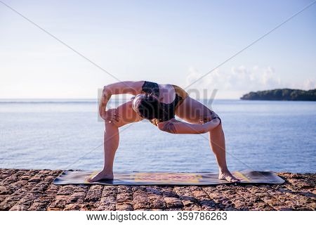 Sunrise Yoga Practice. Young Woman Practicing Parivrtta Utkata Konasana, Revolved Goddess Pose. Open