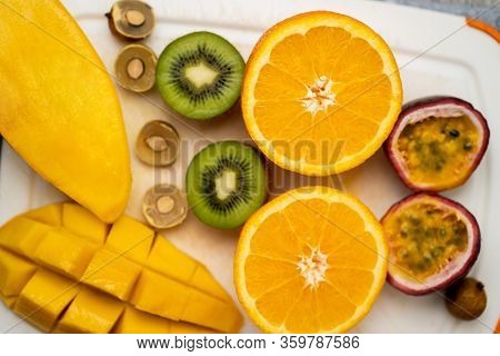 Healthy Vegan Snack Of Raw Tropical Exotic Fruits. Closeup Of Sliced Fresh Mango, Orange, Kiwi, Pass
