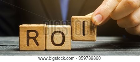 Businessman Puts Wooden Blocks With The Word Roi. Return On Investment Concept. Profitability And Lo