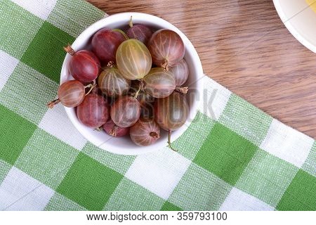 Fresh Gooseberries In White Bowl On Dark Wooden Plate. Top View.