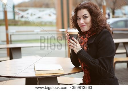 A Very Pretty Woman Laughs Merrily While Reading A Fascinating Book On The Terrace Of A Street Resta