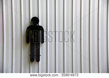 Men Of Sign In Toilet On The White Metal Sheet Background .