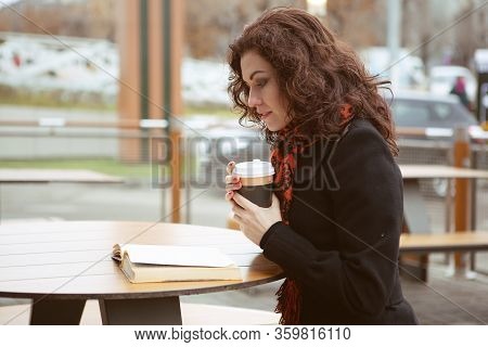 A Very Pretty Woman Laughs Merrily While Reading A Fascinating Book On The Terrace Of A Street Resta