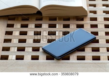 Brech/ Belgium - April 1 2020: A Portrait Of A Smartphone Lying On A Wooden Table Top Next To An Ope