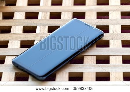 Brech/ Belgium - April 1 2020: A Portrait Of A Smartphone Lying On A Wooden Table Top. The Phone Is 