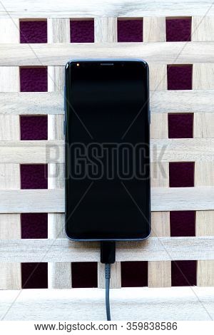 Brecht/belgium - April 1 2020: A Top Down Portrait Of A Smartphone Lying On A Table With A Usb Cable