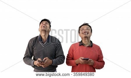 Two Men With Different Ethnicity Looking Up In Joy And Smiling With Phone In Hand Isolated In White 