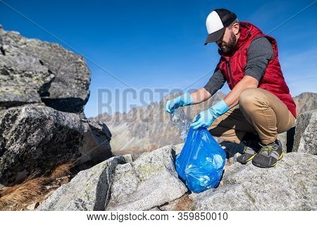 Man Hiker Picking Up Litter In Nature In Mountains, Plogging Concept.