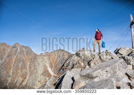 Man Hiker Picking Up Litter In Nature In Mountains, Plogging Concept.