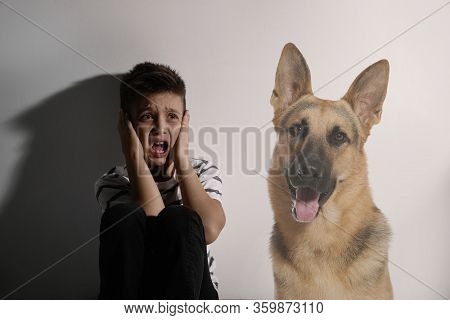 Scared Little Boy Suffering From Cynophobia On White Background. Irrational Fear Of Dogs