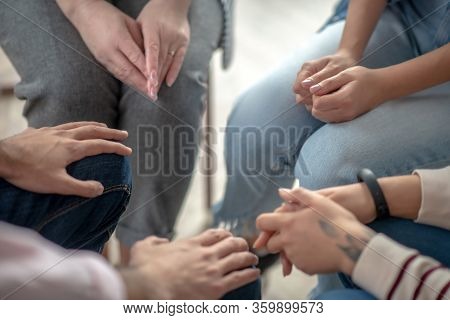 Close Up Picture Of People Sitting In A Circle Close To Each Other