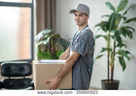Delivery Courrier In A Cap Holding A Big Box In His Hands