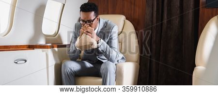 Panoramic Shot Of Stressed African American Businessman Breathing With Paper Bag While Having Panic 