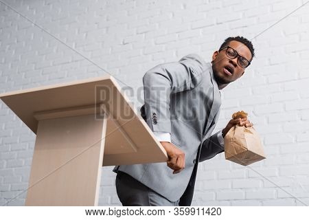Scared African American Speaker Holding Paper Bag And Having Panic Attack During Business Conference